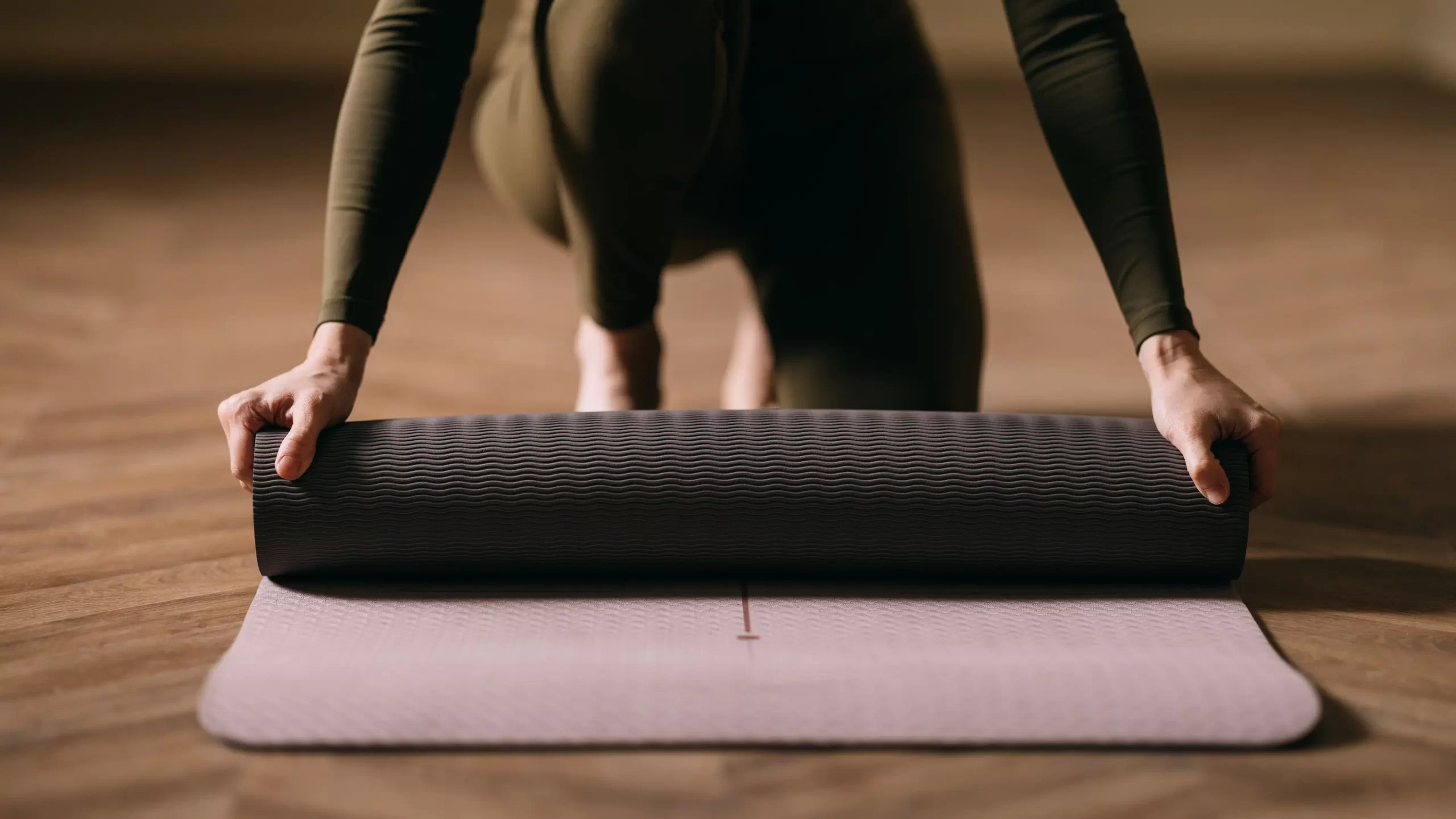 Woman unrolling a purple yoga matt.