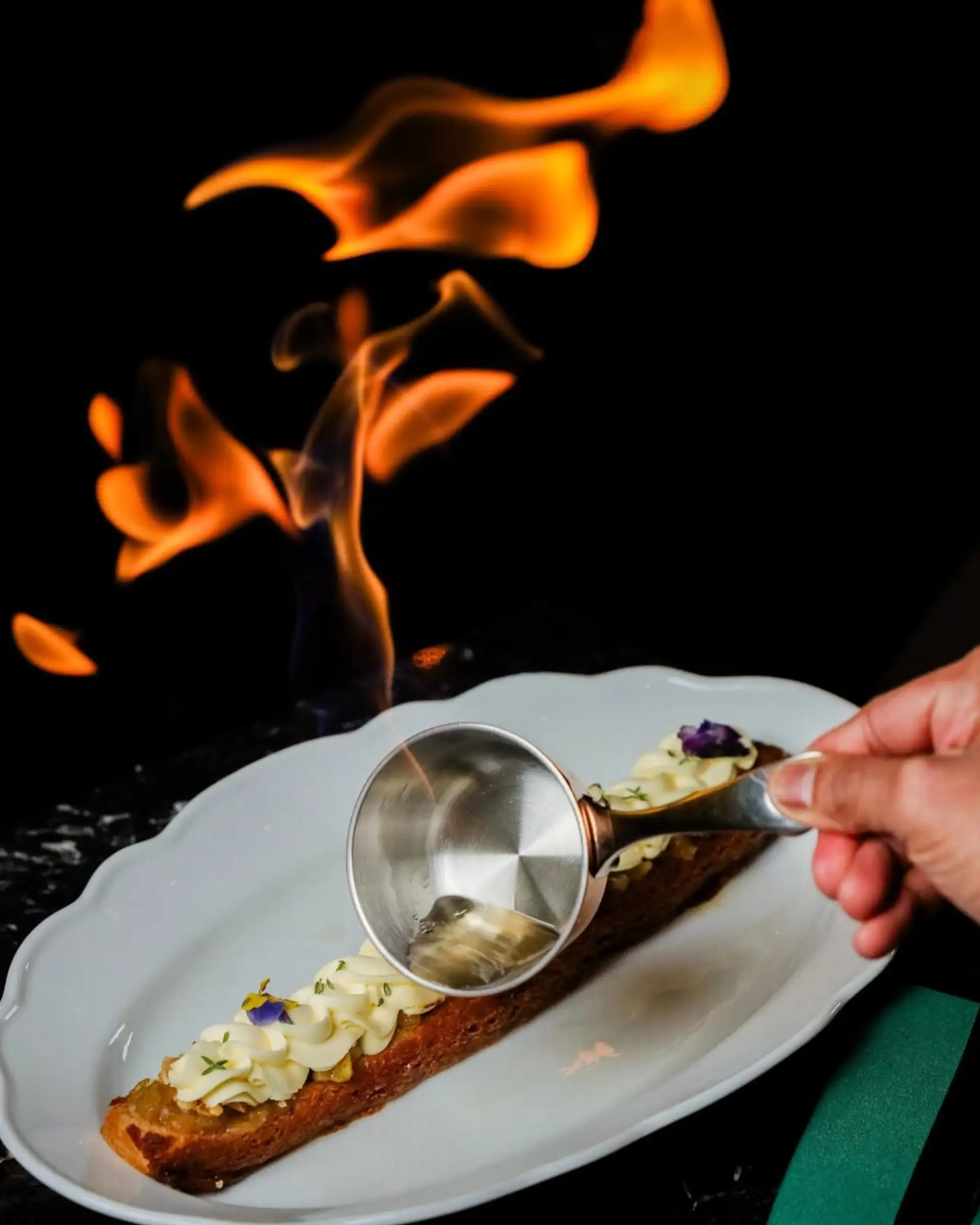 Food on a plate with fire in the background.
